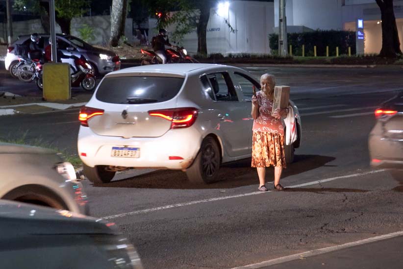 Entre os carros, sinal aberto e fechado, Dona Olinda retrata uma parcela de brasileiros idosos, que dependem de subempregos