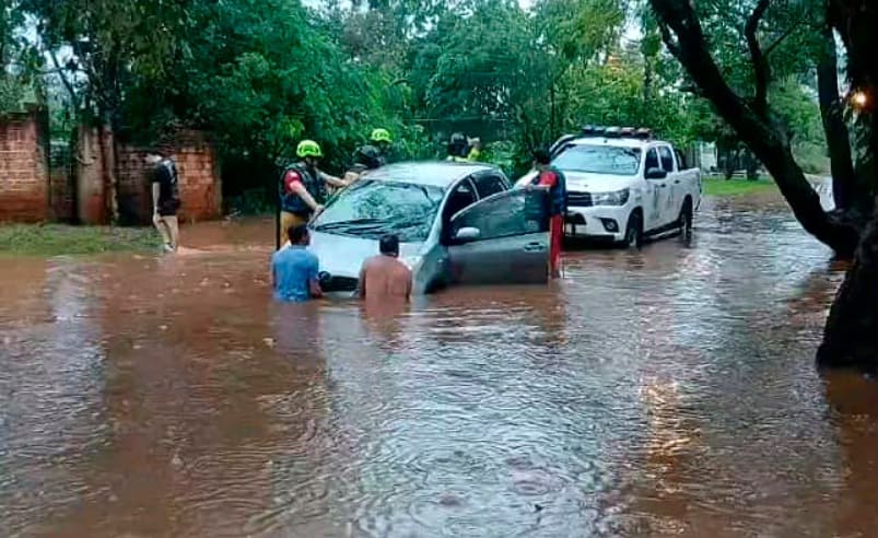 Moradores e equipe policial tentam retirar veículo preso em meio à correnteza em Ciudad del Este.