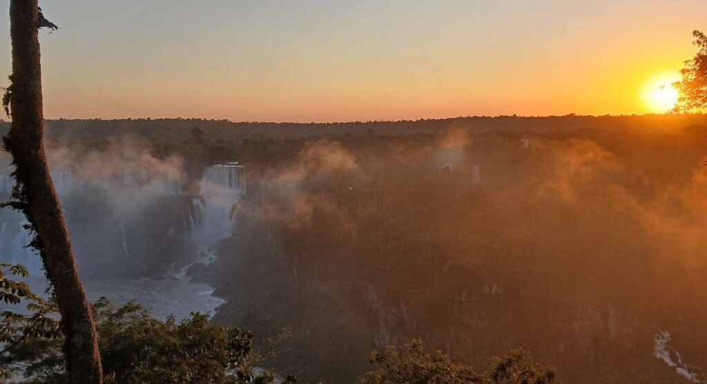 Fim de tarde nas Cataratas do Iguaçu, com os tons alaranjados do entardecer.
