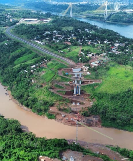 Vista aérea do canteiro da ponte sobre o Monday, com a Ponte da Integração ao fundo.