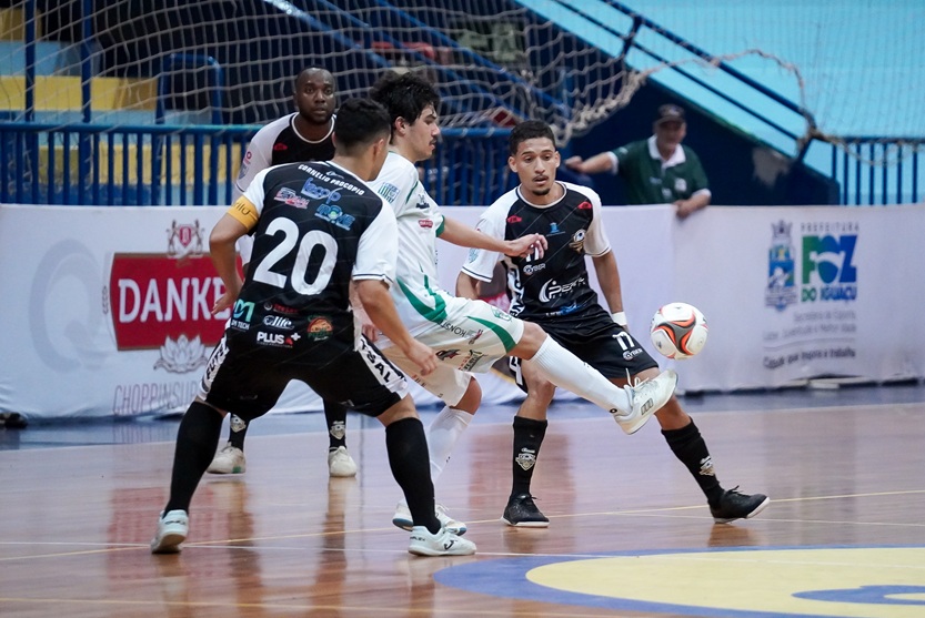 Sob o olhar de três marcadores, MG domina a bola para o Foz Futsal.